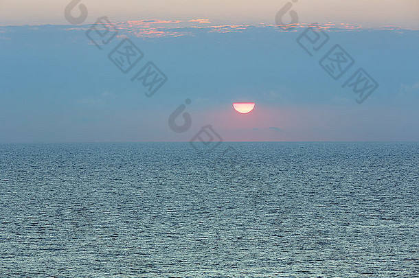 日出的海景和天空中红边的太阳。
