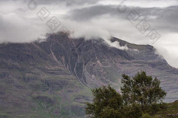 苏格兰安纳特——2012年6月10日：巨大的棕绿色山墙特写，顶部是云层。前面绿树成荫。