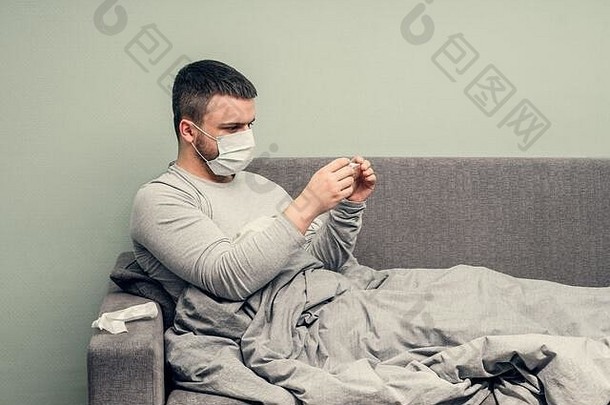 病在家里欢呼。一个年轻人生病了，在家里接受治疗。用餐巾纸擤鼻子，流鼻涕。传染病，流行病，芽孢杆菌携带者。