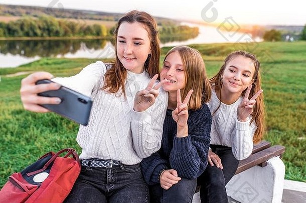 3个女孩12 13 14岁，夏天，手持智能手机，自拍照片。假日周末，最好的朋友，快乐的心情开心的微笑