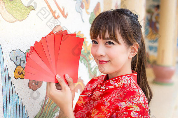 中国新年快乐，可爱微笑的亚洲女人穿着传统旗袍和旗袍，手持红包或红包