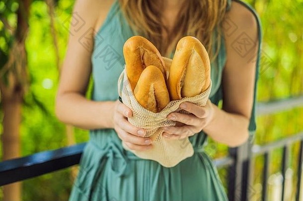 可重复使用的食品袋，一个年轻女子手里拿着面包。零浪费购物。零废物概念