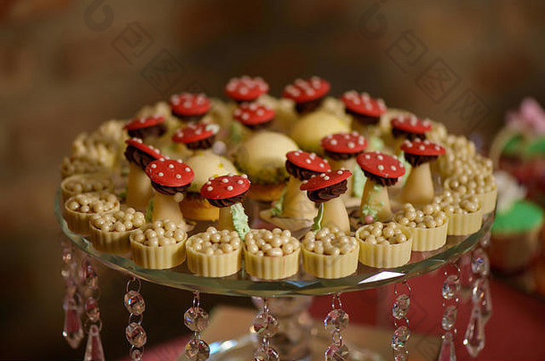 美味的甜点，各种好玩的或主题的一口大小的蛋糕和白巧克力杯，陈列在装饰的水晶蛋糕架上