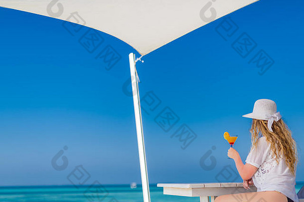 女人在海边放松，热带度假和度假理念。戴着白帽子拿着鸡尾酒的女人。