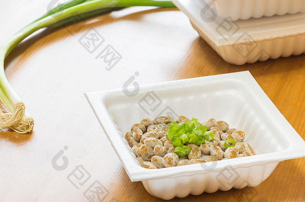 纳豆-一种流行且健康的日本食品，用发泡胶容器中的发酵豆制成，顶部是大葱。