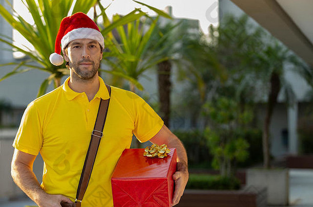 打扮成圣诞老人的巴西邮递员正在送礼物。在线购买正在交付。