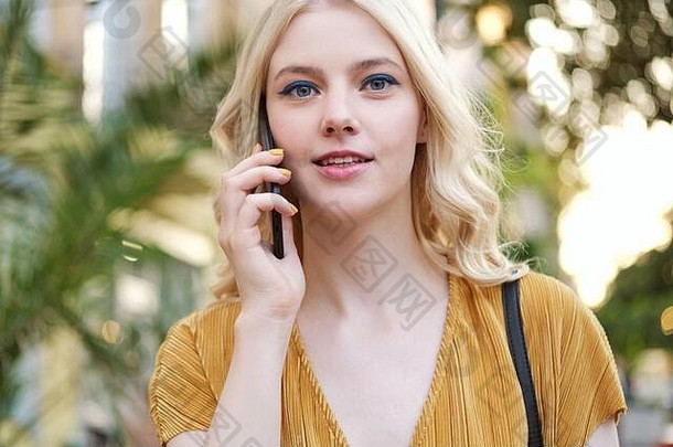 肖像美丽的金发碧眼的女孩深思熟虑相机会说话的手机户外