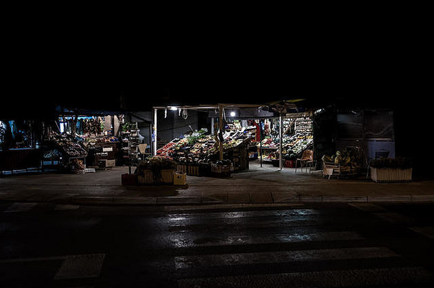 在克罗地亚废弃的道路下，在漆黑的夜晚，摆着水果和蔬菜的市场摊位