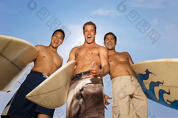 冲浪者站持有冲浪板在户外笑低角视图