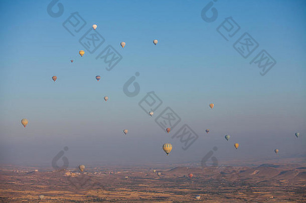 日出时热气球在土耳其卡帕多西亚飞行的彩像。