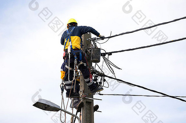 一名男子在顶部电线杆上工作