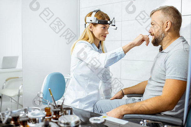 女耳鼻喉科医生在耳鼻喉科办公室的手术室对一名成年患者的鼻子进行医学检查