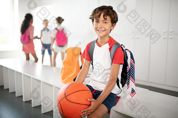 黑发男孩，背着背包，手里拿着篮球