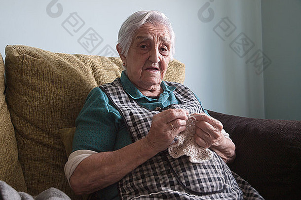 在家里<strong>做针线</strong>活的老妇人。老太太正在看照相机。
