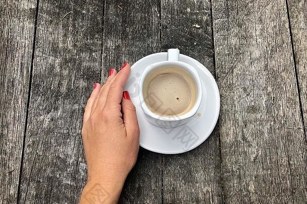 乡村木桌上一杯咖啡旁的女人的手