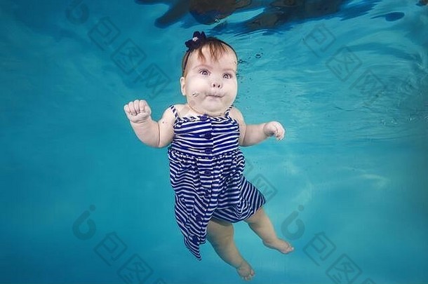 穿着太阳裙的可爱胖乎乎的小女孩在游泳池里潜入水下