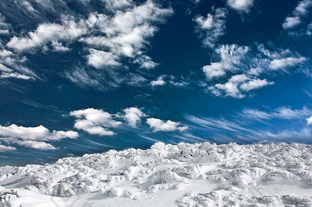 冰雪覆盖的山丘和多云的蓝天的冬季景观
