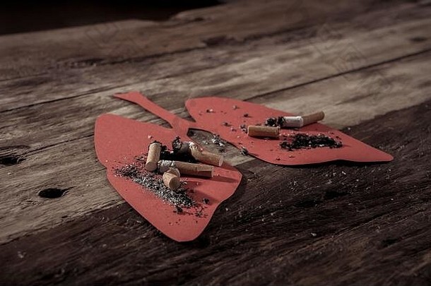 烟蒂和燃烧在乡村背景上隔离的红肺上的概念图像。烟草与肺癌、医疗战的广告风格