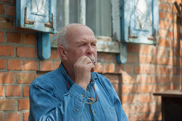 户外肖像上了年纪的乌克兰农民坐着房子吸烟香烟