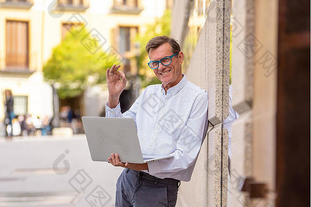 时尚的老人正在使用笔记本电脑在城市户外使用现代技术在数字游牧老人家中上网保持连接和安全