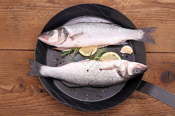 两条新鲜莫罗尼亚科鱼放在煎锅上，配料齐全，俯视图
