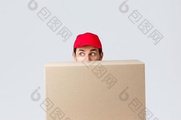 包裹和包裹2019冠状病毒疾病的运送和检疫。戴着红色制服帽的快递员吓了一跳，躲在客户订单后面，向左看