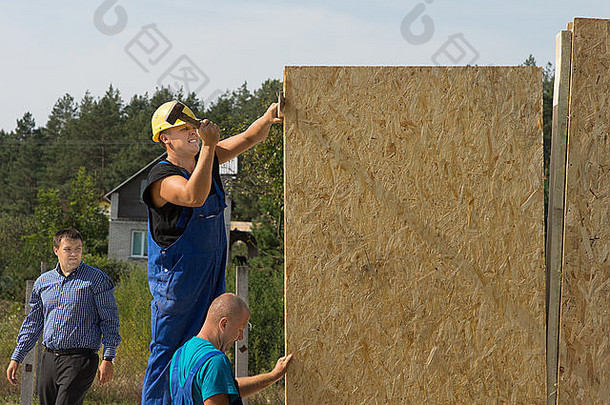 建设工人装配预制墙绝缘木材定位面板安装