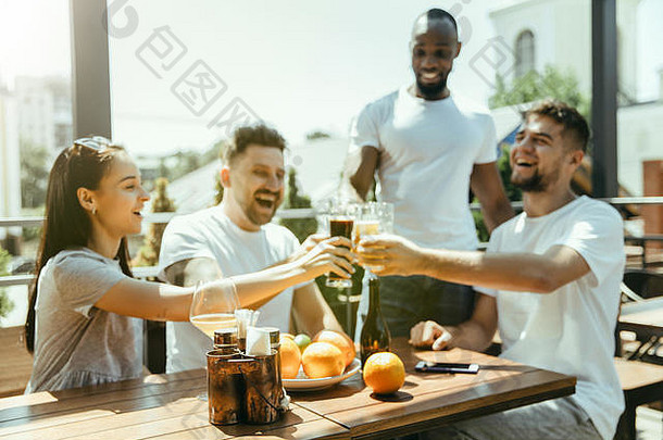 年轻的朋友们一起喝啤酒，玩得开心，欢笑和庆祝。在阳光明媚的日子里，女人和男人都戴着啤酒杯。啤酒节，友谊，团结，幸福，夏日概念。