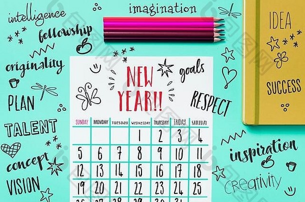 蓝色桌子上的一月日历的高角度视图，旁边是一些不同颜色的铅笔蜡笔、一个黄色记事本和一些新年礼物