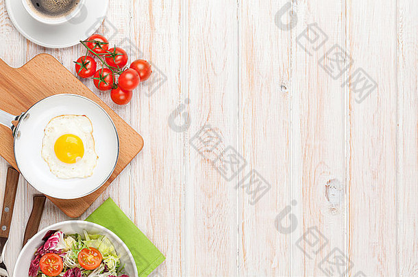 健康早餐，配有煎蛋、西红柿和沙拉，放在白色木桌上，并留有复印空间
