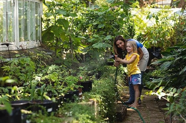 一位白人妇女和她的女儿在阳光明媚的花园里一起看植物