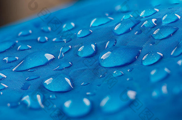 水滴在防水尼龙织物上。蓝色机织合成防水服纹理的宏观细节视图。带有水滴的防水织物。R