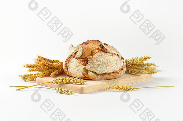 在木制砧板上放着刚烤好的面包和成熟的玉米穗
