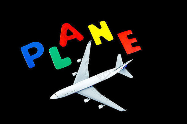 黑色的玩具飞机，上面用木刻字母拼出飞机