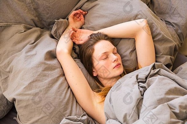 年轻的女孩睡觉卧室灰色床单