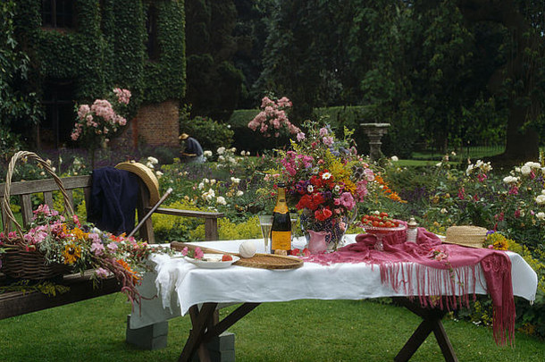 夏天的乡村花园，草坪上摆着桌子，午餐用的是白布和几瓶酒