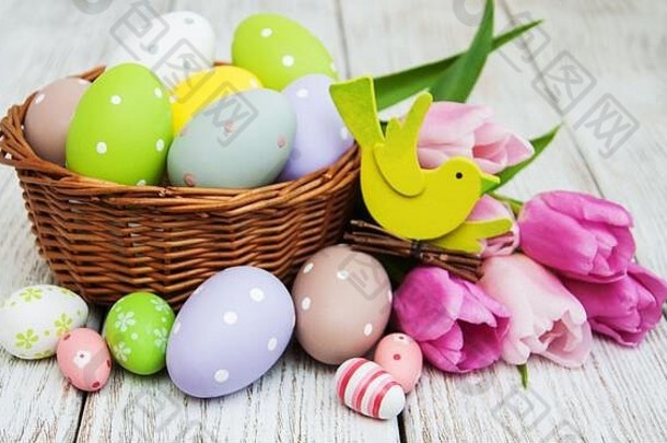 木桌上放着复活节彩蛋和郁金香的篮子