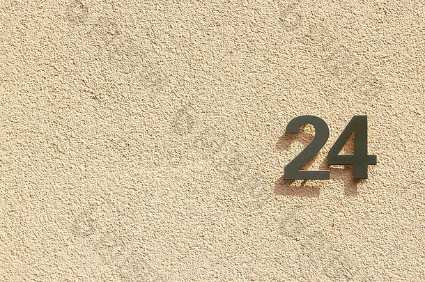 24号房子，24个银色金属数字，在浅橙色的石膏墙上投下阴影