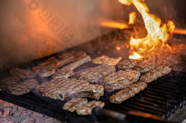四个烤牛肉串混合的顶视图，在热的烧烤木炭烤架上，在黑色背景上隔离出明亮的火焰。夏季部分的概念