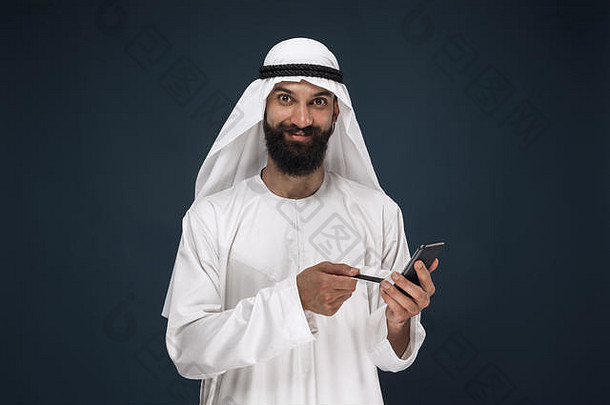肖像阿拉伯沙特商人黑暗蓝色的工作室背景男人。智能<strong>手机支付</strong>比尔在线购物押注概念业务金融面部表达式人类情绪