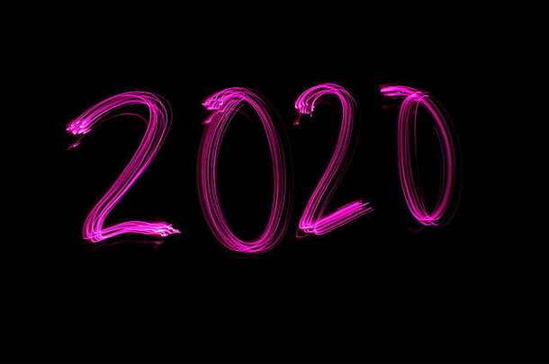 数字“2020”的长曝光照片，在黑色背景下呈霓虹粉红色。光绘摄影。