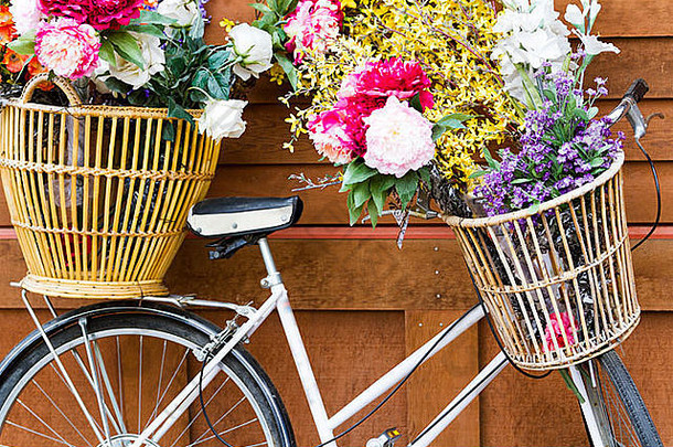 一辆旧自行车，上面有一篮篮鲜艳的花。