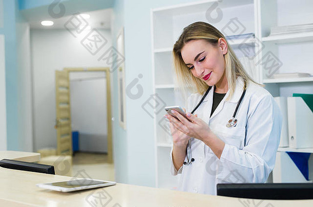 一位面带微笑的女医生戴着刷子在医院接待处工作，她正在剪贴板上写一份医疗报告并安排预约