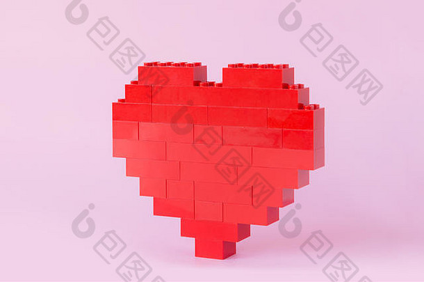 粉红色背景下，一颗由玩具建筑砖制成的红心的侧视图。