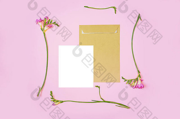 粉红色背景上的白色信纸和环保纸信封的平面照片。带粉色百合花的邀请函或情书。