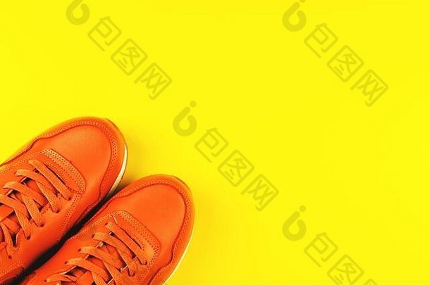 黄色背景的橙色运动鞋。运动和健康生活方式的概念。放置文字、平面布局、俯视图。