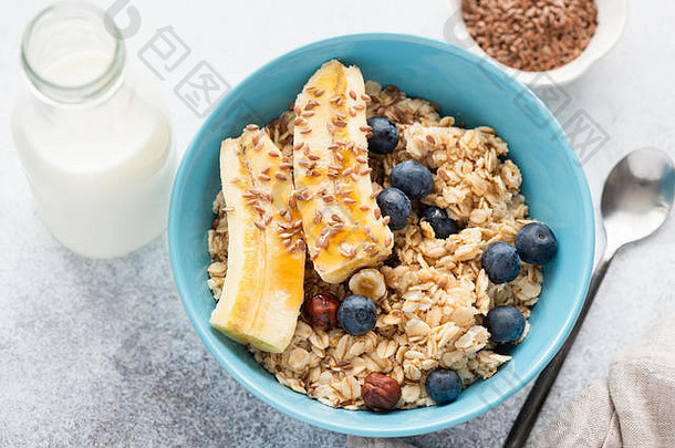 燕麦配香蕉、蓝莓、亚麻籽和榛子。健康、美味、营养的早餐。俯视图，特写