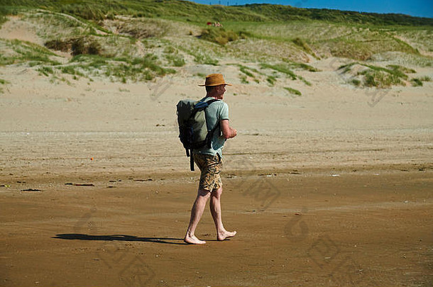 中间岁的高加索人男人。背包稻草他走光着脚海滩沙子热<strong>夏天</strong>阳光