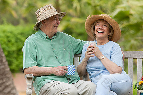 上了年纪的夫妇坐着板凳上花园
