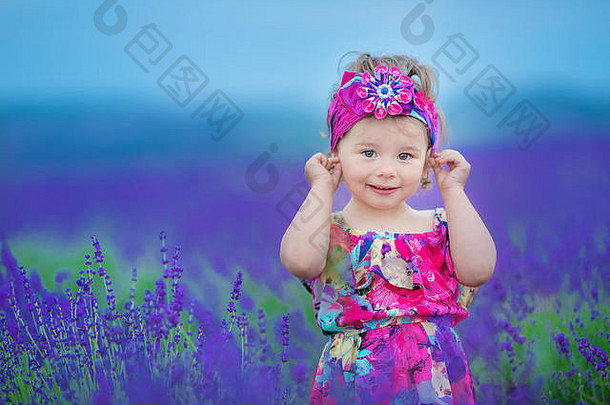 时尚的婴儿女孩一年走薰衣草场穿乡村色彩斑斓的衣服他相机微笑在开玩笑